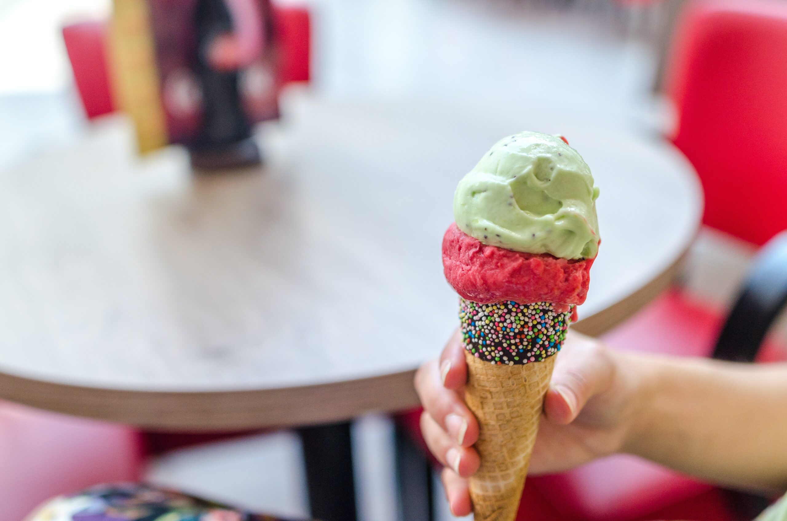 Image d'un cornet de glace tenu par la main d'une personne proposé par la crèmerie.